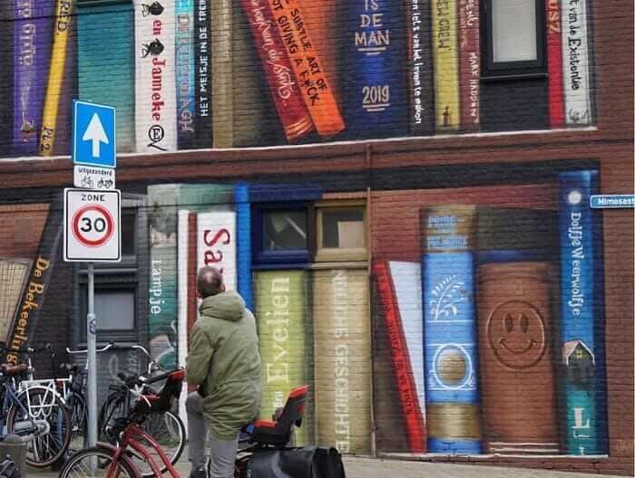 contioutra.com - Artistas holandeses pintam uma prateleira gigante em um prédio de apartamentos com livros favoritos dos moradores