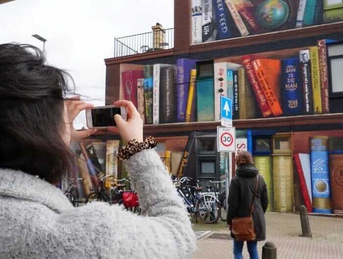 contioutra.com - Artistas holandeses pintam uma prateleira gigante em um prédio de apartamentos com livros favoritos dos moradores