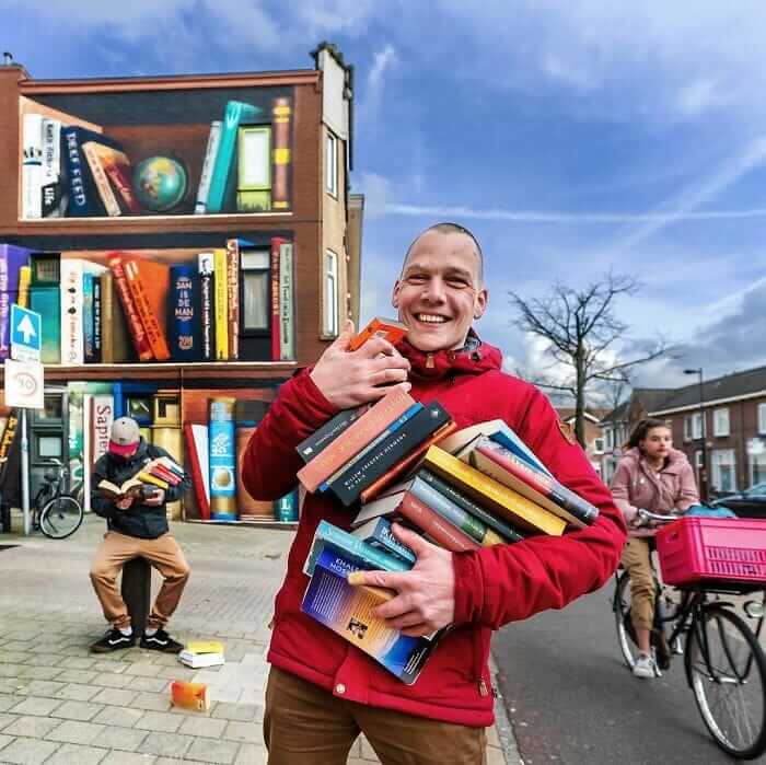 contioutra.com - Artistas holandeses pintam uma prateleira gigante em um prédio de apartamentos com livros favoritos dos moradores